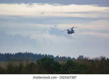 RAF Chinook UH-1 helicopter flying low in a cloudy blue grey and white winter sky on a military exercise, Wiltshire UK