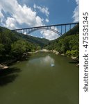 Rafters float towards the rapids under the high arched New River Gorge bridge in West Virginia