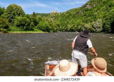 Rafting river Vah on wooden rafts. Castle Starhrad at background