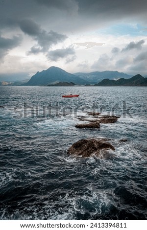 Rage waves of the ocean splashed on the rocks, Keelung mountain  in the background, in Keelung city, Taiwan.