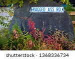 Ragged Ass Road sign from Yellowknife Canada on a rock with fall colored shrubs