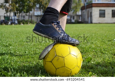 Ragged sneakers with a soccer ball on the football field