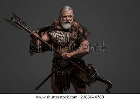 A raging shouting silver-haired bearded Viking warrior in fur and light armor against a gray backdrop