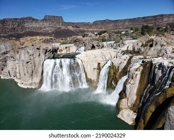 The Raging Waterfalls And Mountainous Backdrop Of Shoshone Falls And The Western Snake River In Twin Falls, Idaho As Viewed From The Landing Under A Very Clear, Blue Summer Sky