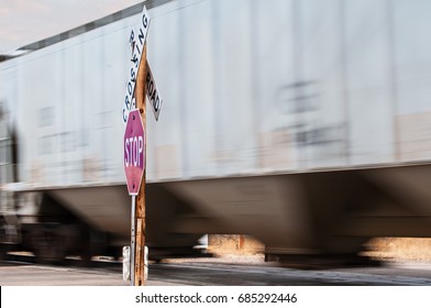 Rail Cars Carrying Bulk Freight At A Railroad Crossing Marked By A Stop Sign And RR Warning