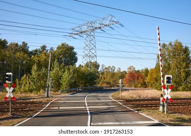 Rail crossing with high voltage power transmission line in background.