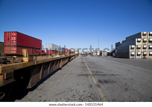 Rail yard with containers loaded onto train with\
flat deck trucks