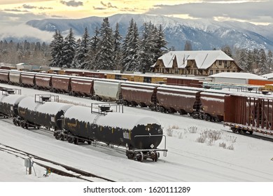 rail yard in winter with trains, depot, and mountains in background Whitefish, Montana