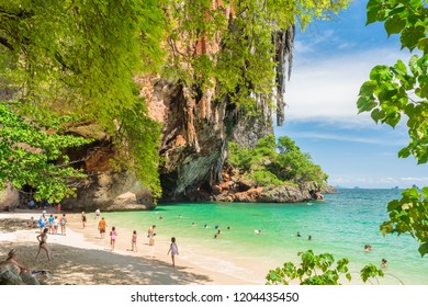 Railay, Thailand - July 3, 2018: tourists walk and swim on Phra Nang (Phranang) Beach with its evergreen vegetation, rocky mountain, stalactites and the Princess Cave.