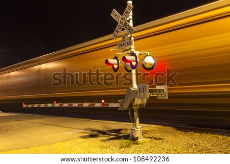 railroad crossing with passing train by night