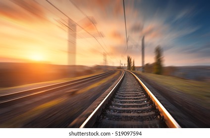 Railroad in motion at sunset. Railway station with motion blur effect against colorful blue sky, Industrial concept background. Railroad travel, railway tourism. Blurred railway. Transportation - Powered by Shutterstock