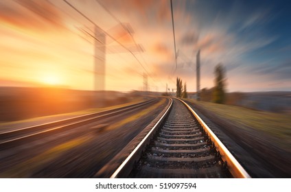 Railroad in motion at sunset. Railway station with motion blur effect against colorful blue sky, Industrial concept background. Railroad travel, railway tourism. Blurred railway. Transportation