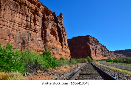 The railroad runs along the red mountains in Utah, in the distance is a man between the rails. Utah USA - Powered by Shutterstock