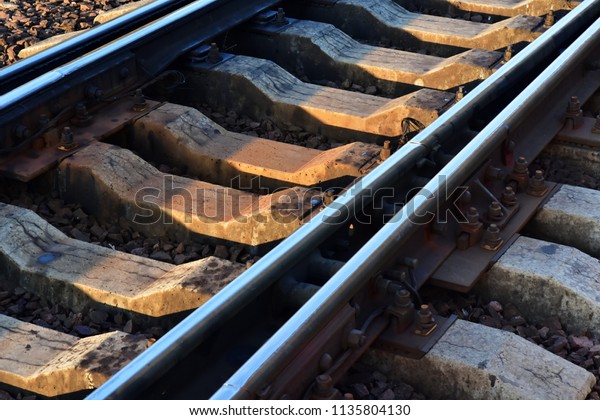 Railroad switch closeup. Rails on cracked old\
concrete sleepers