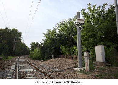 Railroad track passing through a patch of trees between buildings in an italian town on a cloudy day