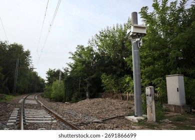 Railroad track passing through a patch of trees between buildings in an italian town on a cloudy day