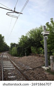 Railroad track passing through a patch of trees between buildings in an italian town on a cloudy day
