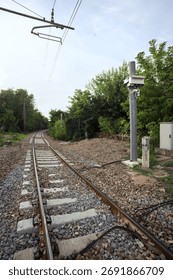 Railroad track passing through a patch of trees between buildings in an italian town on a cloudy day