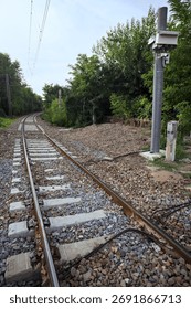 Railroad track passing through a patch of trees between buildings in an italian town on a cloudy day