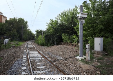 Railroad track passing through a patch of trees between buildings in an italian town on a cloudy day