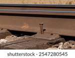 Railroad tracks with spike sticking up. Railway maintenance, track repair and transportation infrastructure safety concept.