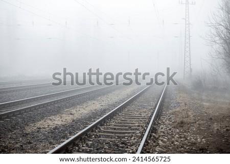 Railroad tracks without a train in daytime winter fog.