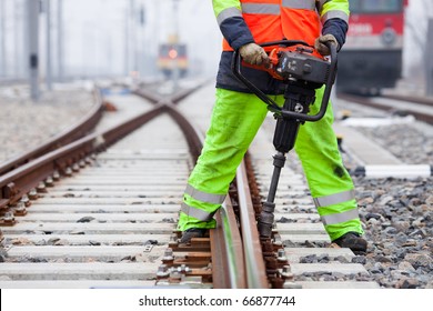 The Railroad Worker Fixes A Screw On The Rails