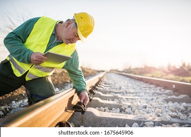 Bahnarbeiter, die Eisenbahnen kontrollieren. Benutzer von Tablet-Systemen