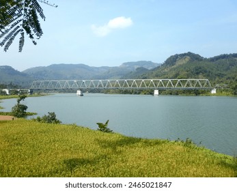  The railway bridge over the Serayu River in the Indonesian city of Purwokerto looks like hills behind it.                               - Powered by Shutterstock