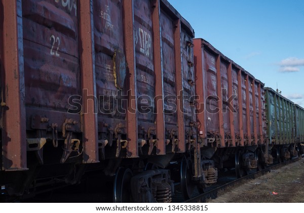 Railway cars . Railway. Set of cars. Old rumpled red\
brown freight cars train containers. Industrial background image of\
the perspective of a freight train, and above him  blue clear sky.\
Railroad. 