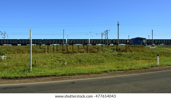 Railway crossing.\
Freight train goes on rails. Automobile paved road passes in\
parallel. The Eastern\
Siberia.