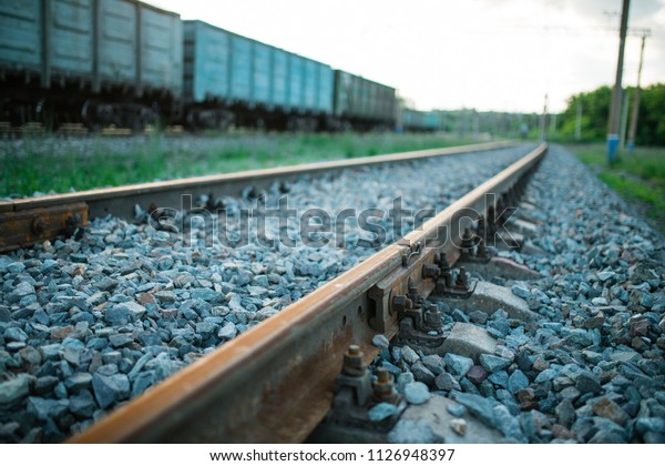 The railway engine of a freight locomotive that\
crosses the desert during sunset.\
Large transport of goods in\
tanks by rail. railway\
rails