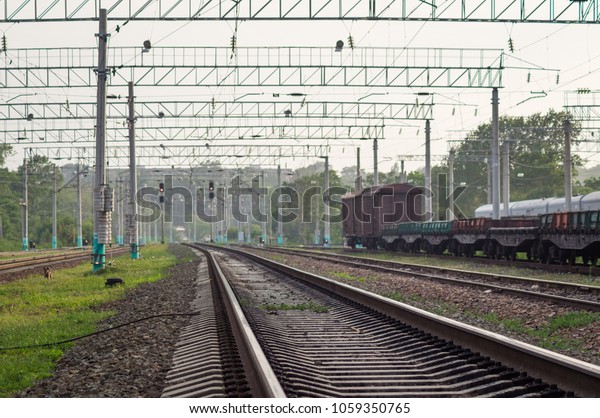 The railway and the\
railway freight train in the summer. In the background, a red\
traffic light