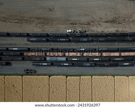 railway fuel cars at a transloading facility, the train tracks are beside a ranchers wheat field. 
