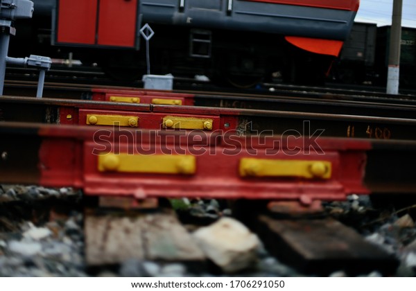 Railway
rails, sleepers, rail fastening, red and yellow, against the
background of gravel and barely noticeable lower edge of the
passenger electric train with red
elements.