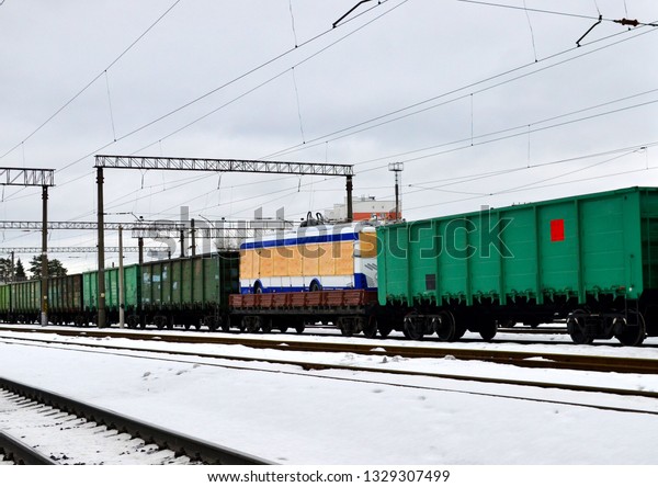 Railway station, freight train wagons, trolley\
bus on a railway platform. Logistics of delivery of the truck,\
transportation of \
machinery