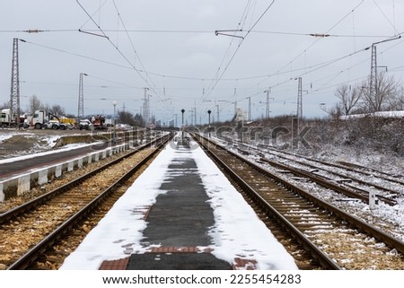 Railway station platform with incoming train partially covered with snow, in Bulgaria, January 28 2023