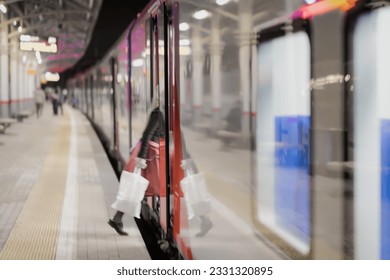 Railway subway station, at night, at dusk, passenger train stopped. Unrecognizable girl enters the train. Passenger transportation, style of life. Blurred background