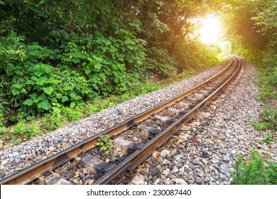 Railway track crossing rural landscape under evening sunset sky - Powered by Shutterstock