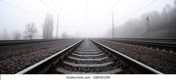 The railway track in a misty morning. A lot of rails and sleepers go into the misty horizon. Fisheye photo with increased distortion - Powered by Shutterstock