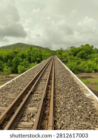 A railway track passing a bridge through the lush green forest of Gir, Gujarat, India, surrounded by trees and natural vegetation. Scenic railway infrastructure through a peaceful forest landscape.