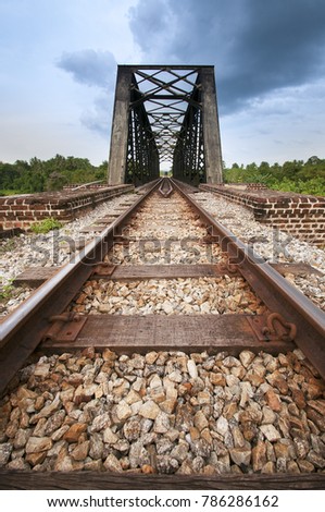 Railway track and solid steel bridge for conventional train with the stones and blue cloudy sky.