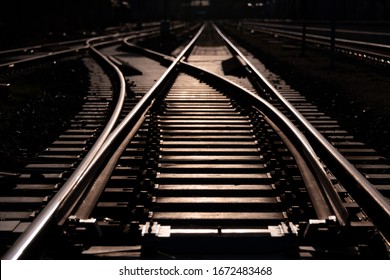 Railway track and switches at a station in Letmathe Sauerland Germany with geometrical structure and vanishing point. Low sunlight reflected by sheer steel surface of rails, screws and thresholds. - Powered by Shutterstock