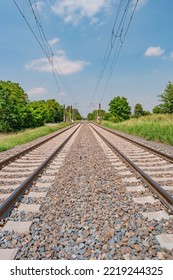 Railway For Trains In Beautiful Farm Landscape With Rapeseed Yellow Field And Poppy Red Flowers In Summer, At Sunny Day And Blue Sky