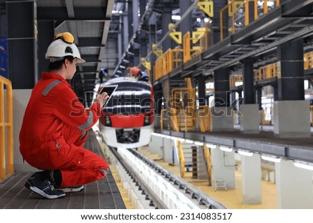 Railway worker with tablet computer . Railway employee in working clothes works with tablet computer. Railway engineer waiting  for the train arrived at platform.