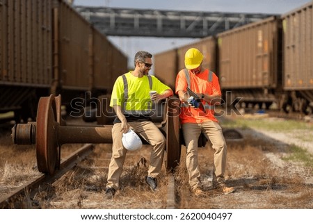 Railway workers checking railway track is level. engineer wearing a safety vest standing confidently on the railway tracks. Shipping worker controlling shipping cargo containers departure