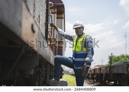 Railway Yard Worker Climbing Train Car with Safety Gear, African American Railroad Engineer Inspecting Freight Train, Man in High-Vis Vest at Train Depot, Industrial Transport and Logistics
