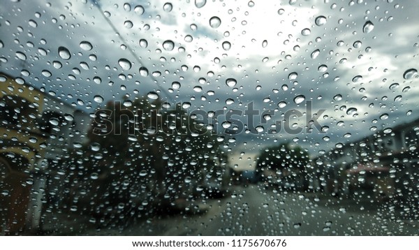 rain behind a window. rain drops on glass. cars on\
the road. heavy rain