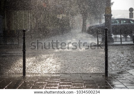 Rain in the city. Road, pavement, car in rain, close up. Water splashes, spills on roadway.