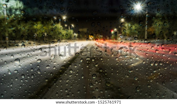 Rain in the\
city as seen from a window, out of focus background with light\
trails, raindrops in the\
foreground